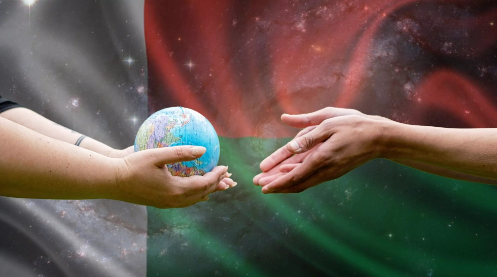 Deux mains tendues se transmettent un globe terrestre sur fond du drapeau de Madagascar, symbolisant la coopération mondiale et le rôle stratégique croissant de l'île dans l'externalisation numérique.