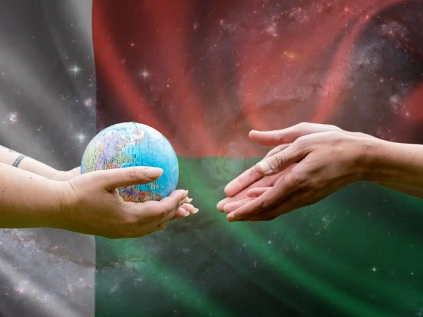 Deux mains tendues se transmettent un globe terrestre sur fond du drapeau de Madagascar, symbolisant la coopération mondiale et le rôle stratégique croissant de l'île dans l'externalisation numérique.